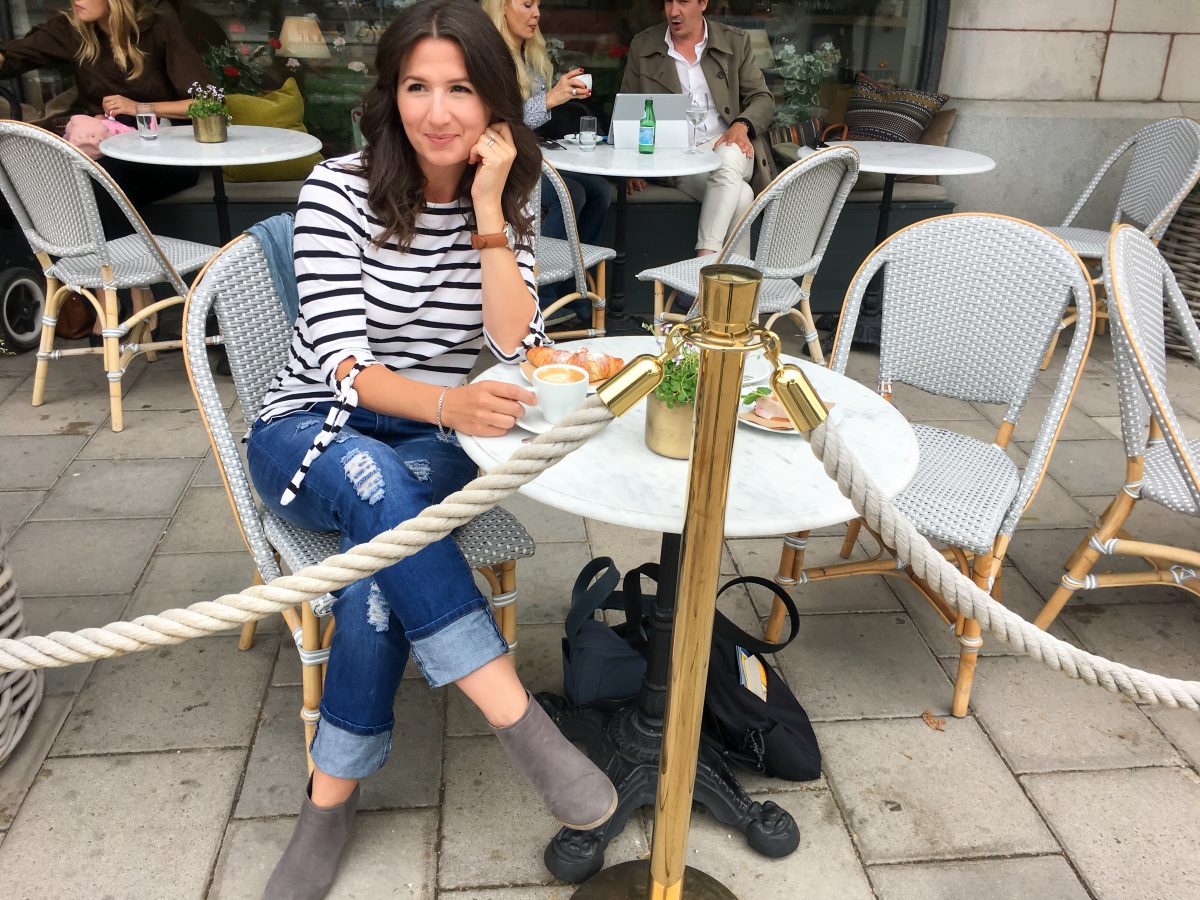 Erin sips a cappuccino at a cafe in Stockholm wearing a nautical striped top.