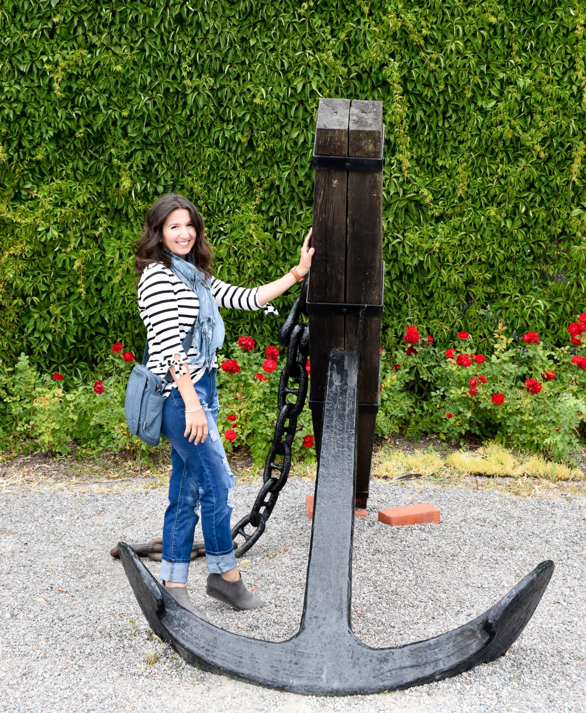 Erin poses with a large vintage anchor in Vaxholm, Sweden wearing a nautical striped tee.