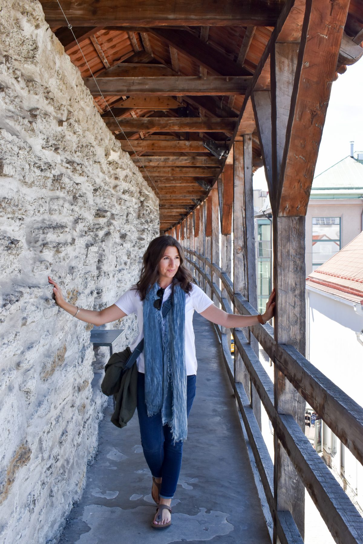 Erin walks the medieval wall in Tallinn Estonia wearing her favorite travel wardrobe essential, a long scarf. 