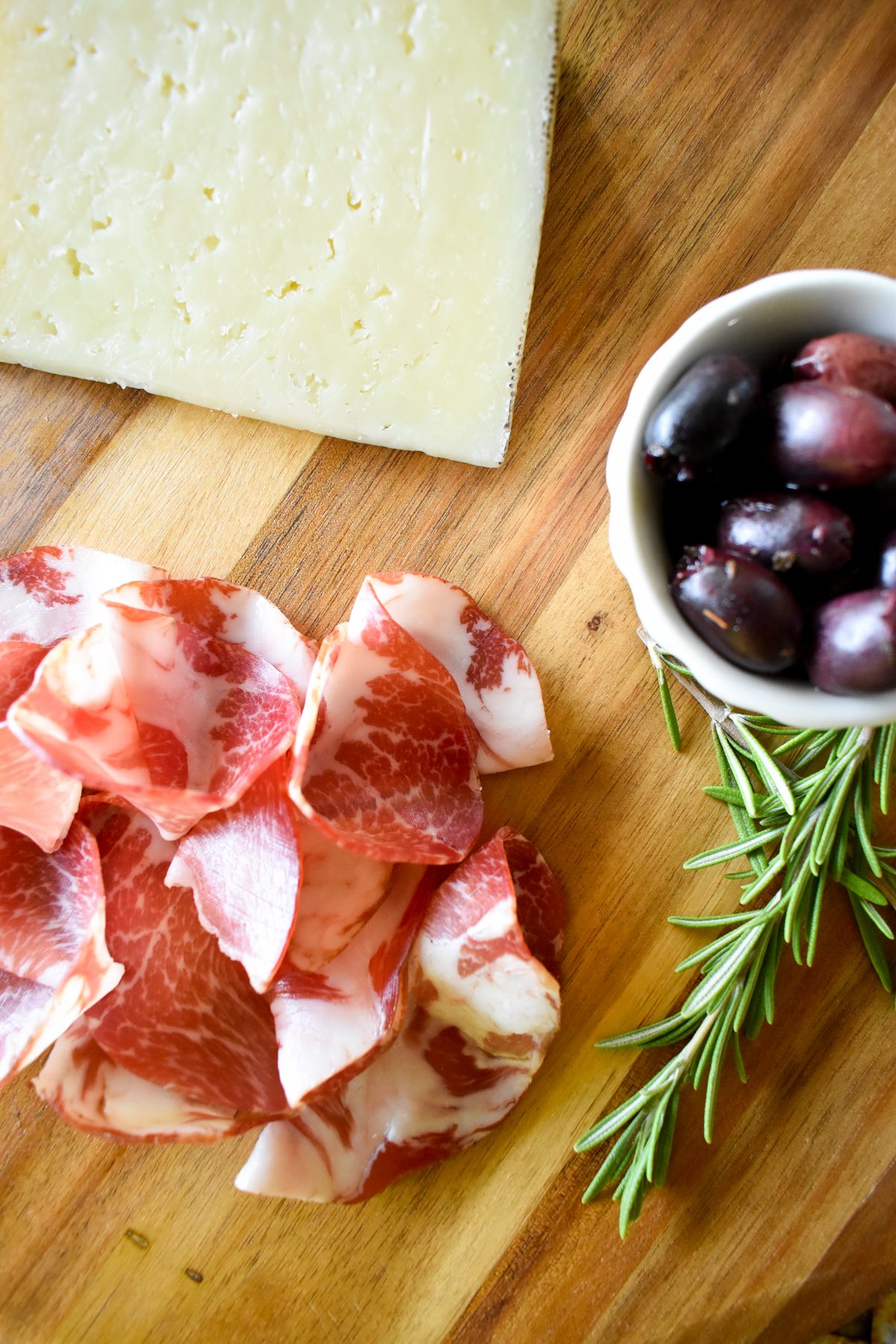 A close up of Erin's charcuterie board showing detail of coppa, manchego, and olives.